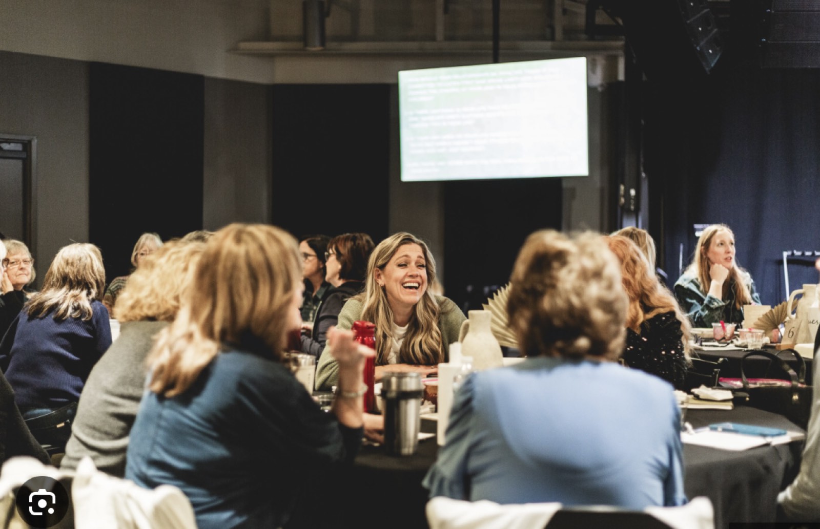 Parents laughing together at round tables during a kickoff night